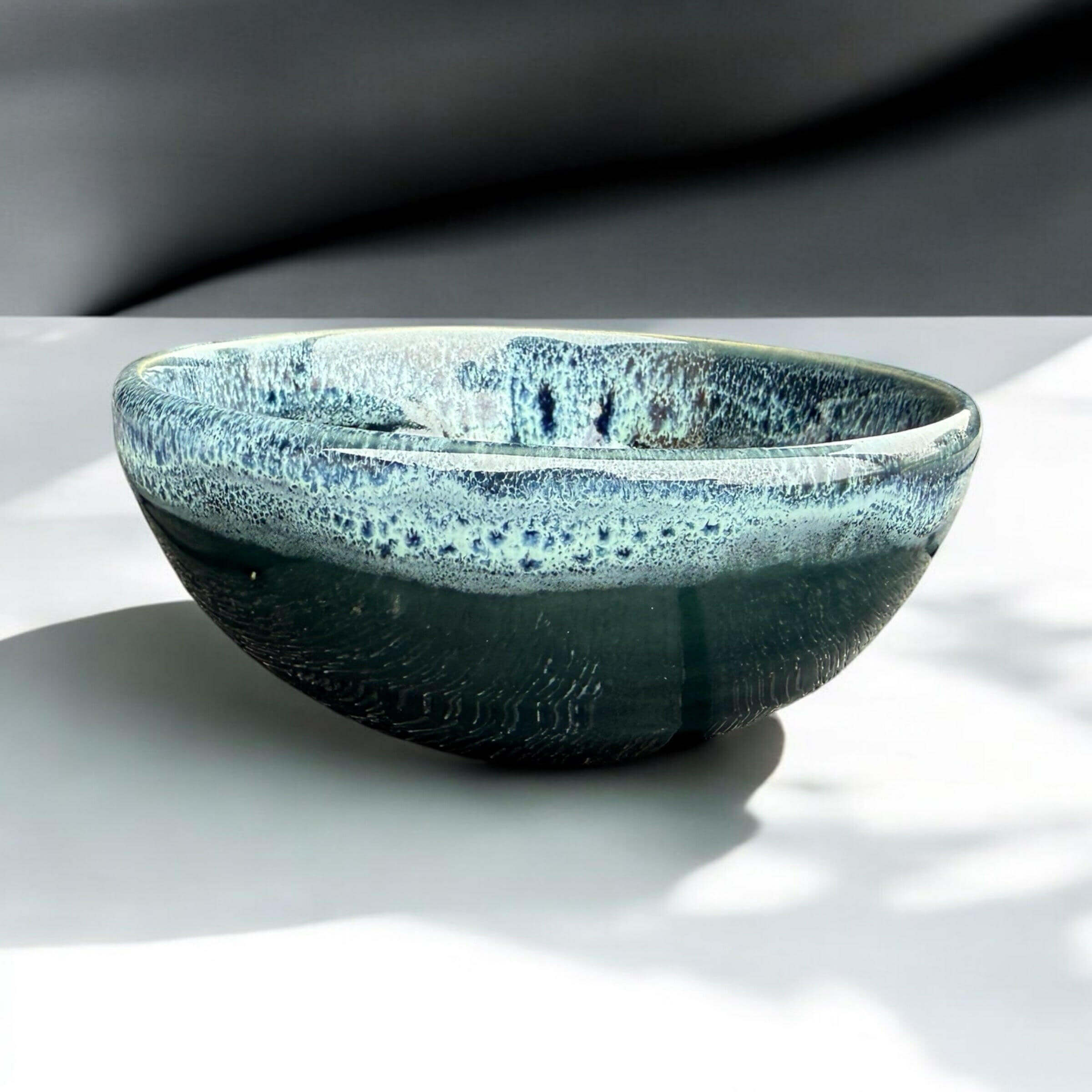 Handmade ceramic bowl with deep blue-green glaze and unique texture, perfect for serving or decoration.