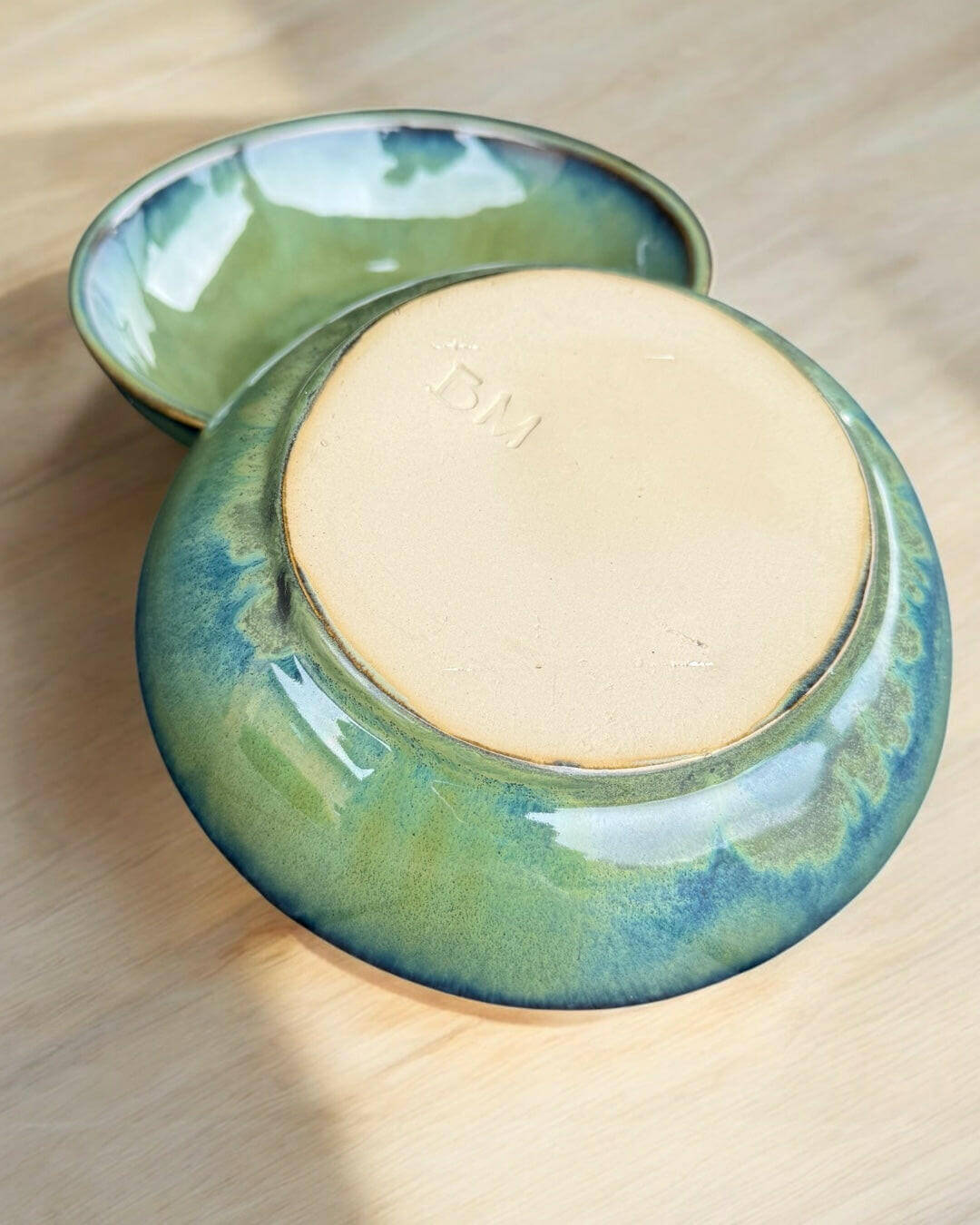 Handmade bowl featuring flowing green and blue hues, ideal for serving or decoration, showcasing a smooth glaze.
