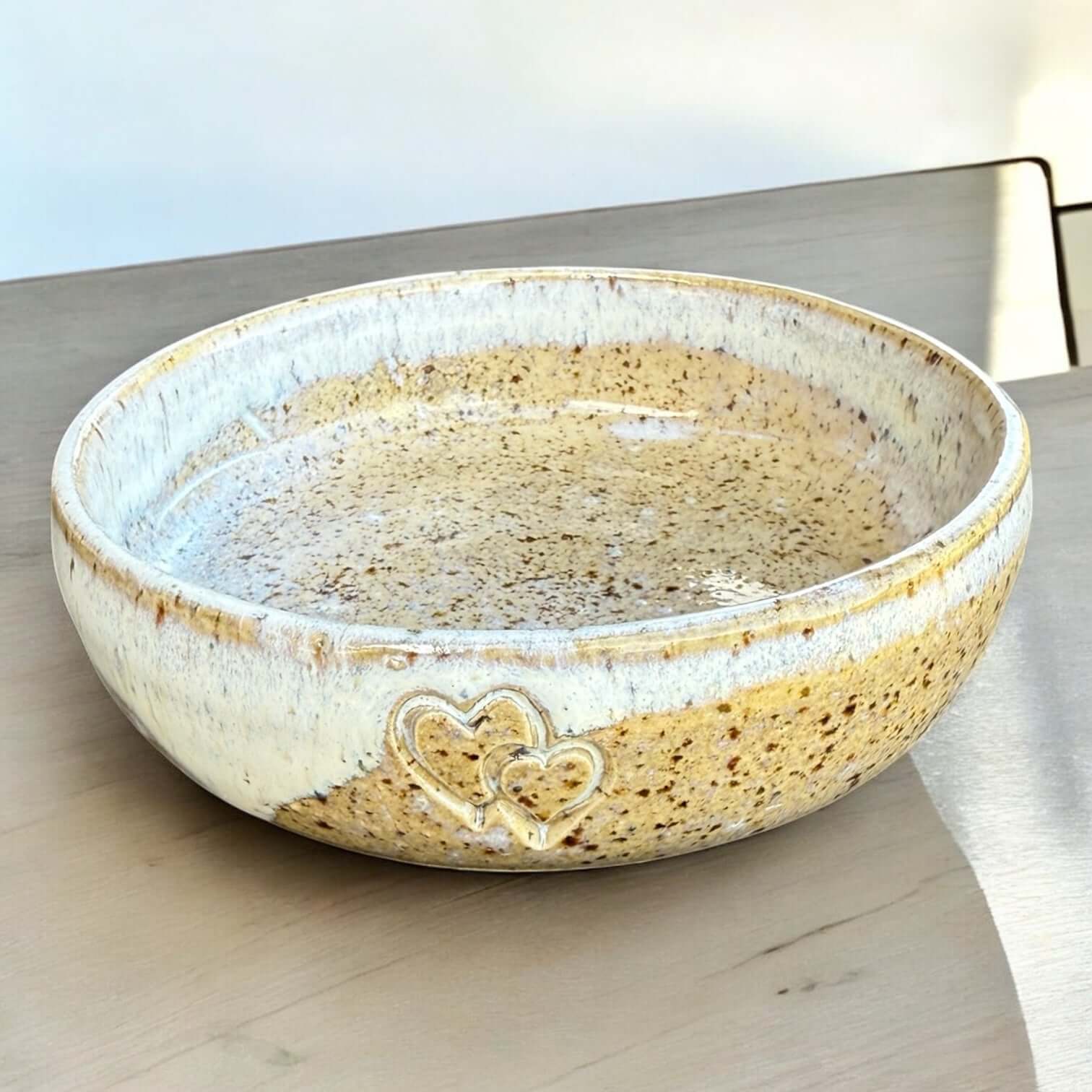 Handmade ceramic pet bowl with speckled glaze and two embossed hearts, ideal for small dogs and cats.