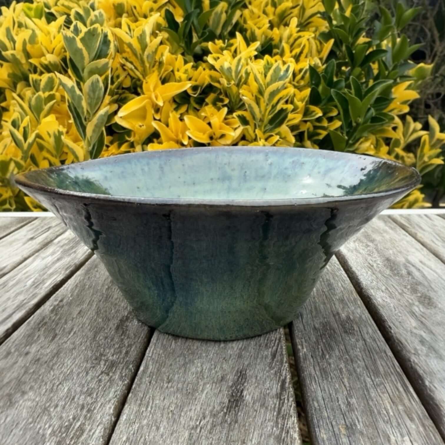 Handmade green ceramic bowl with glossy glaze, ideal for serving salads and decorative display.