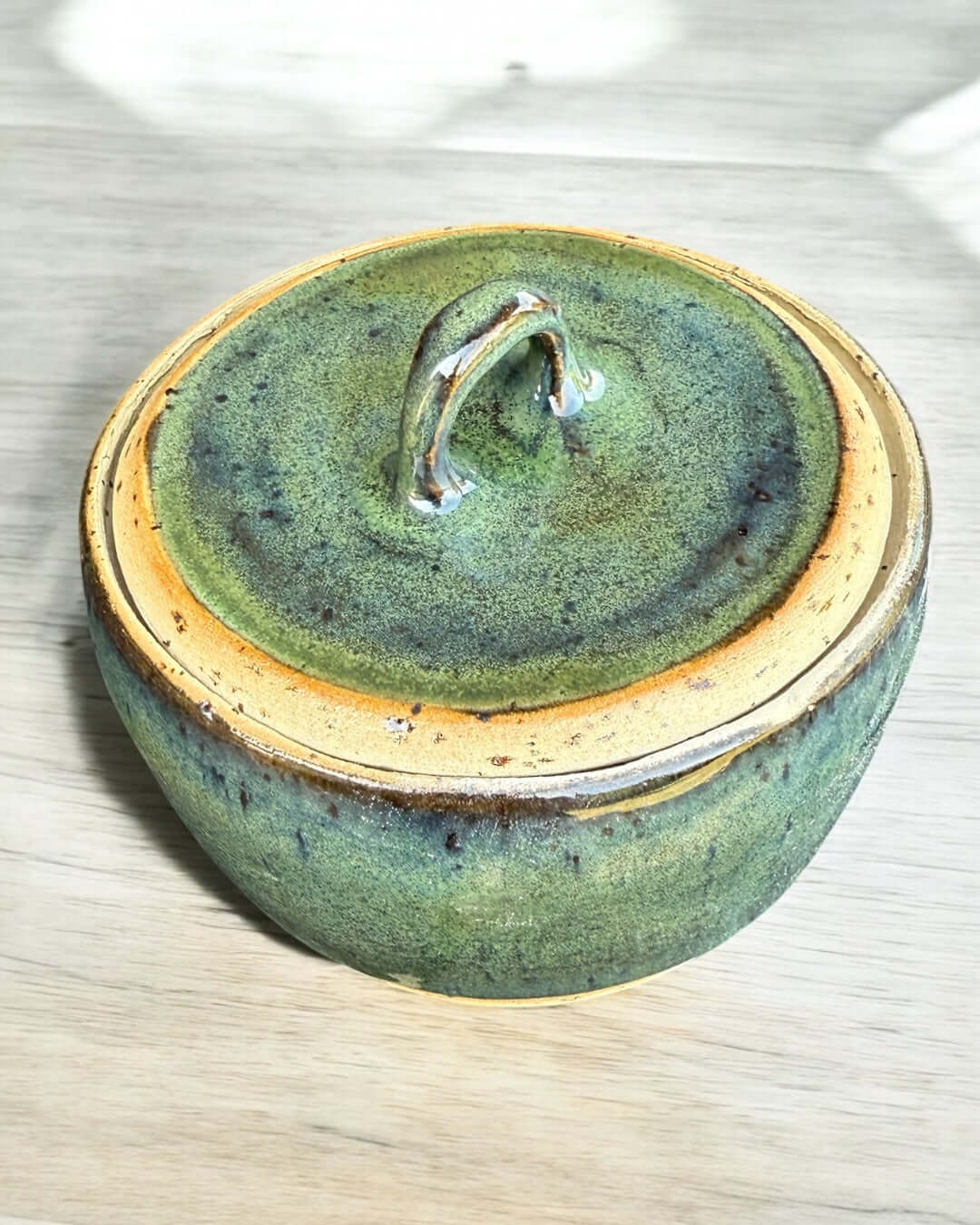 Handmade green ceramic jar with matching lid in seaweed tones, glossy glaze, ideal for kitchen storage or decor.