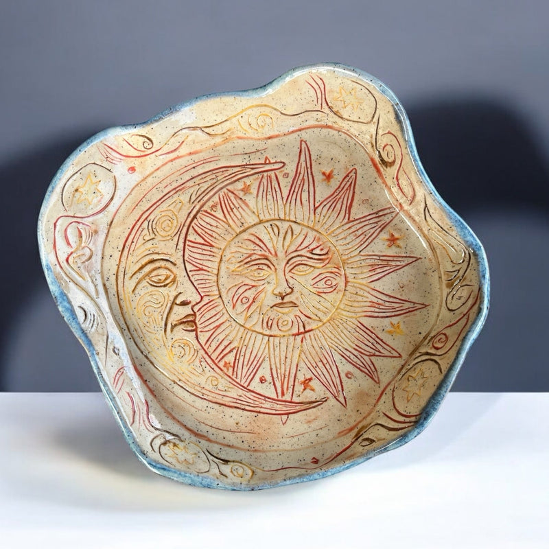 Decorative ceramic plate featuring sun and moon design, perfect for home decor or as a unique art piece.
