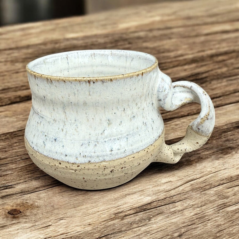 Handcrafted ceramic mug with a unique design, featuring a speckled finish and a curved handle, perfect for dinnerware collection.