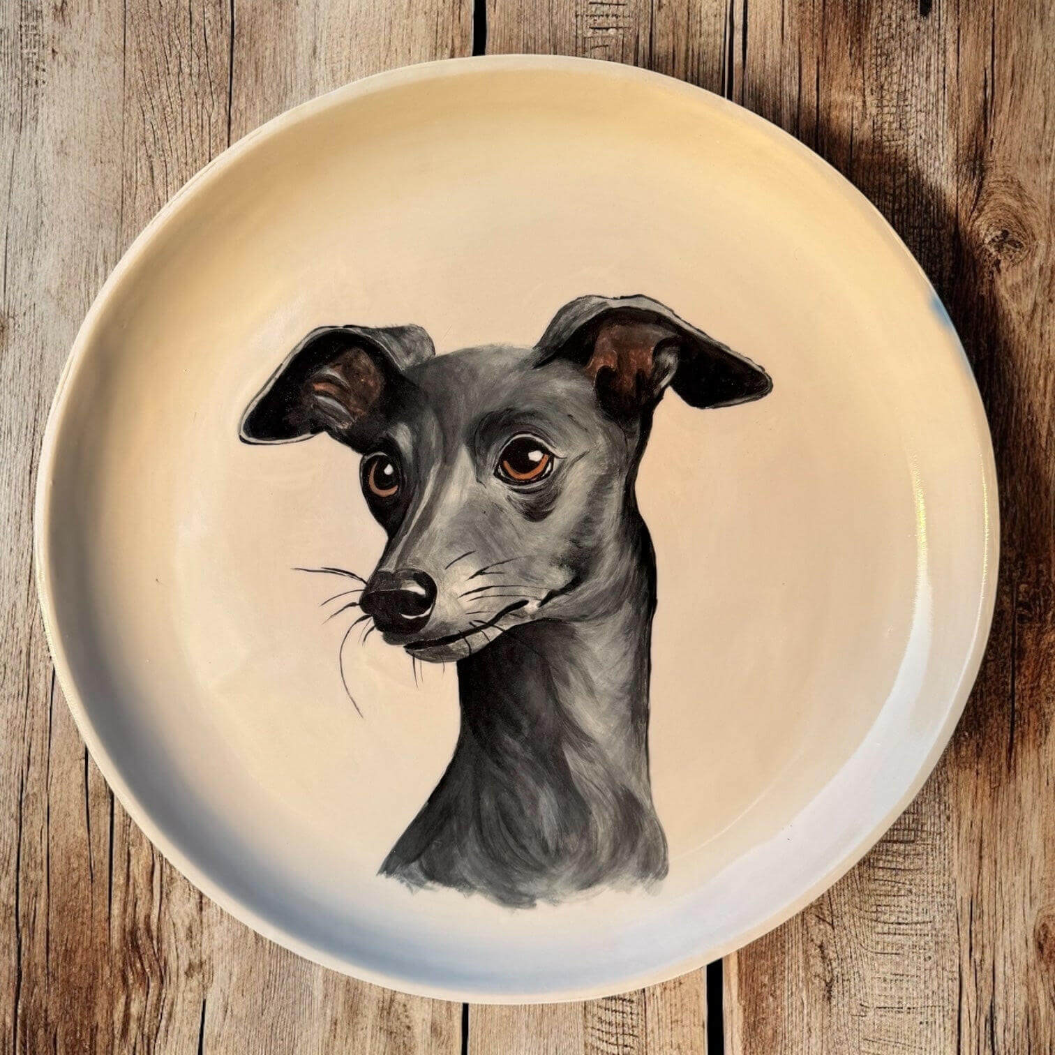 Hand-painted ceramic wall plate featuring a portrait of an Italian Greyhound on a rustic wooden background.