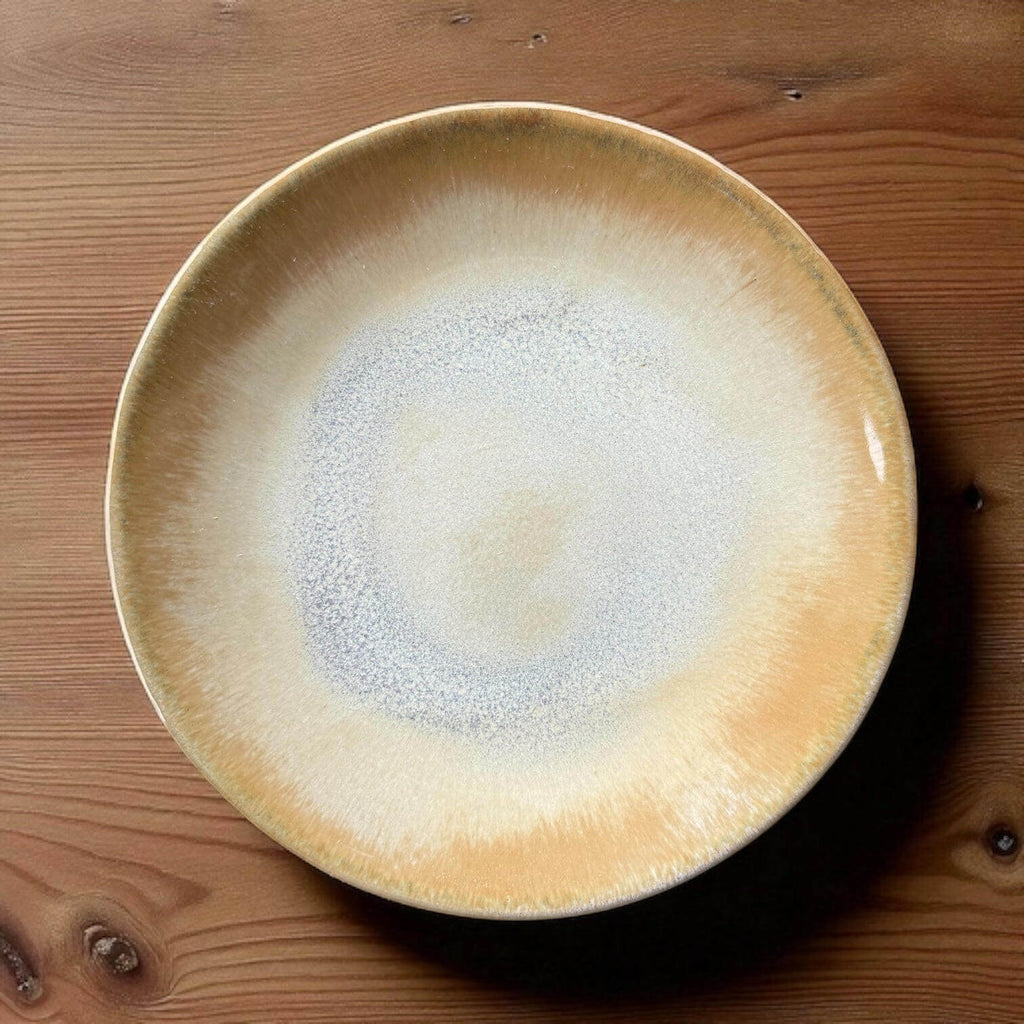 Handmade ceramic plate with creamy beige and misty grey-blue tones, measuring 16 cm, placed on a wooden surface.