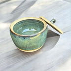 Handmade green ceramic jar with lid, glossy seaweed tones, ideal for kitchen storage or decor.