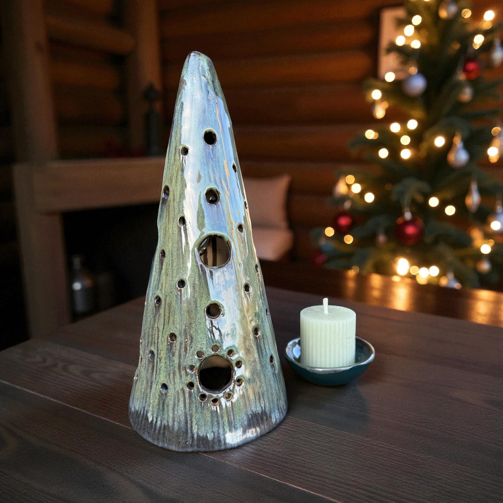 Handmade ceramic tealight tree in forest green glaze with candle on table, casting soft light patterns.