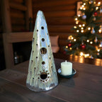 Handmade ceramic tealight tree in forest green glaze with candle on table, casting soft light patterns.