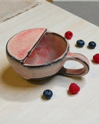 Handmade ceramic berry rinsing mug in soft strawberry glaze with raspberries and blueberries.